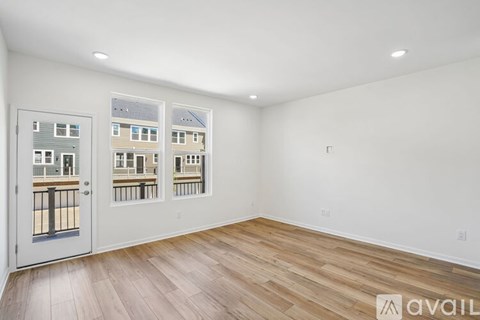 A room with a white door and windows showing a view of a building.