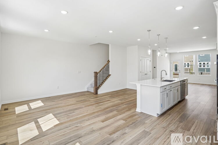 A spacious living room with wooden flooring and a staircase.