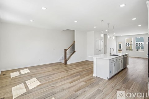 A spacious living room with wooden flooring and a staircase.