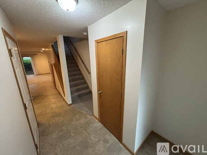 A hallway with a wooden door and a staircase.