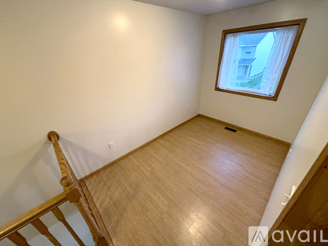 A room with wooden flooring and a window with a view of a building outside.
