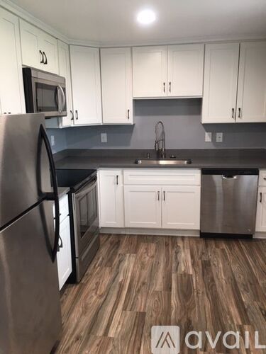 A kitchen with white cabinets and a wooden floor.