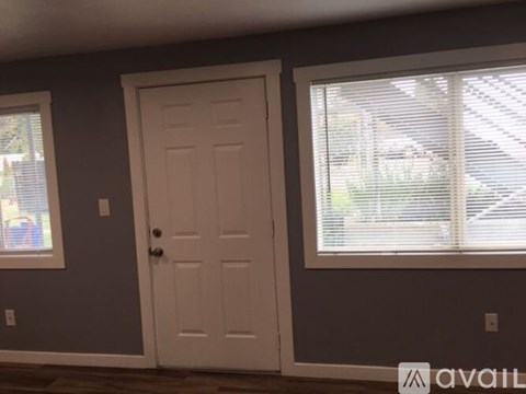 A room with a white door and a window with blinds.