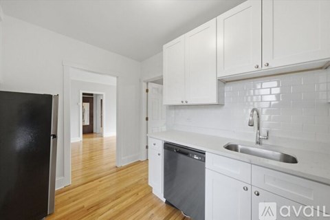 A kitchen with white cabinets and a black refrigerator.