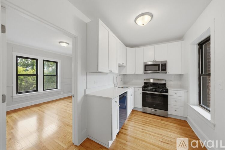 A kitchen with white cabinets and a wooden floor.