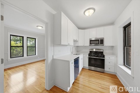 A kitchen with white cabinets and a wooden floor.