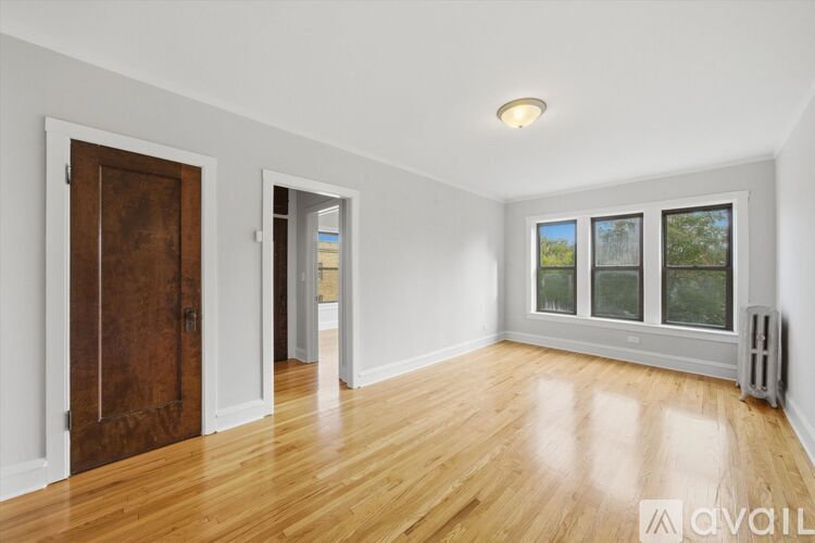 A room with wooden floors and a window with a view of trees.