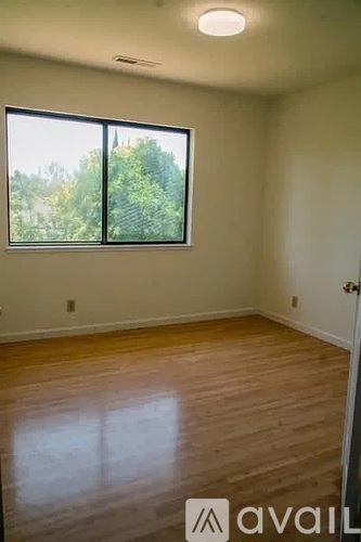 A room with wooden floors and a large window overlooking trees.