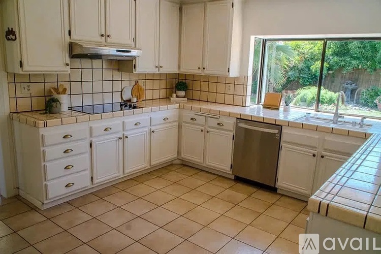 A kitchen with white cabinets and a tile floor.