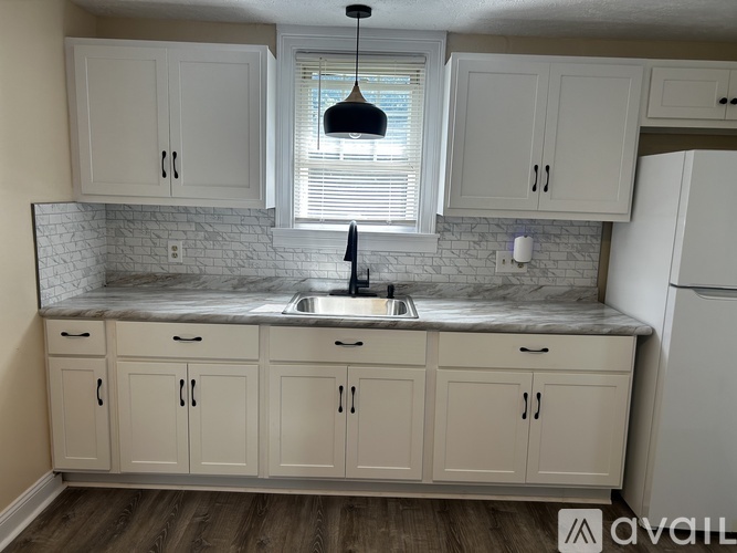A kitchen with white cabinets and a marble countertop.