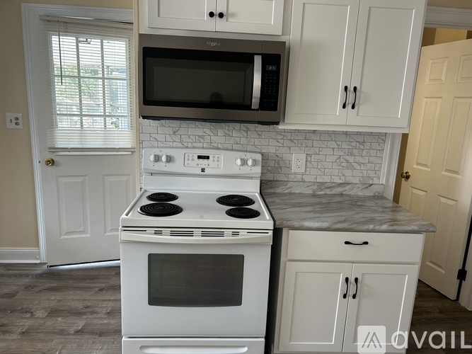A white stove and microwave in a kitchen with white cabinets.
