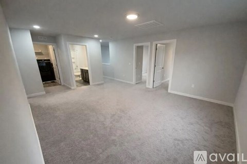 A spacious empty room with carpeted floor and white walls.