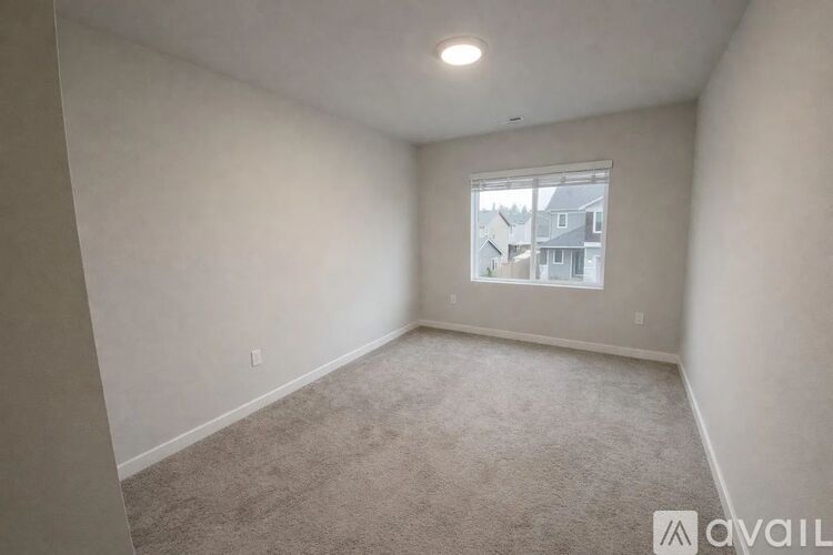 A room with a carpeted floor and a window showing a view of buildings outside.