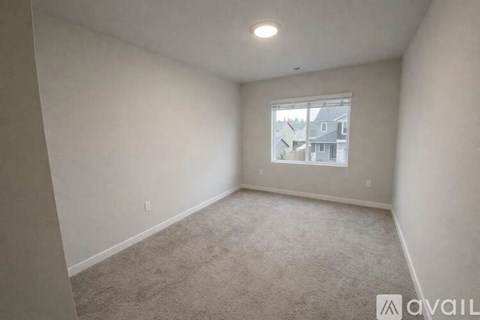 A room with a carpeted floor and a window showing a view of buildings outside.