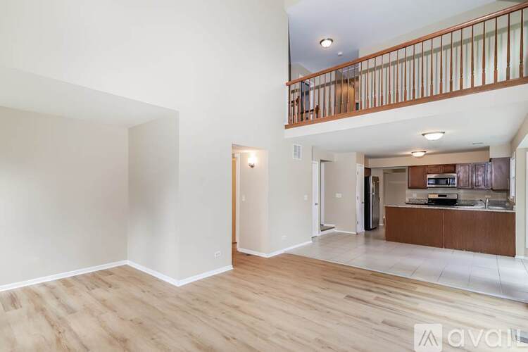 A spacious room with wooden flooring and a balcony with a railing.