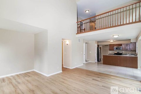 A spacious room with wooden flooring and a balcony with a railing.