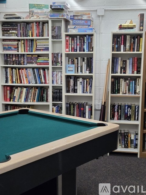 A pool table in front of a bookshelf filled with books.