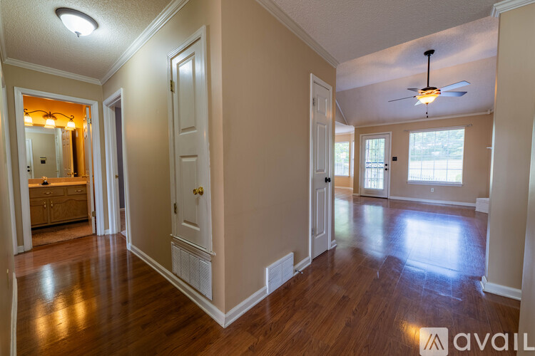 A spacious room with wooden floors and a ceiling fan.