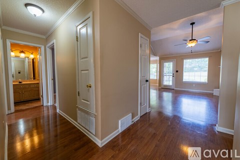 A spacious room with wooden floors and a ceiling fan.