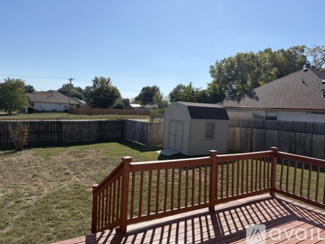 A backyard with a wooden deck and a fence.