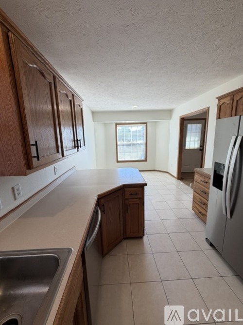 A kitchen with wooden cabinets and a stainless steel refrigerator.