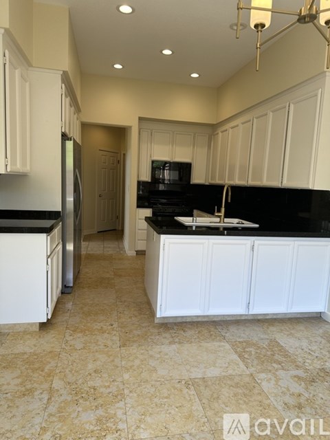 A kitchen with black countertops and white cabinets.