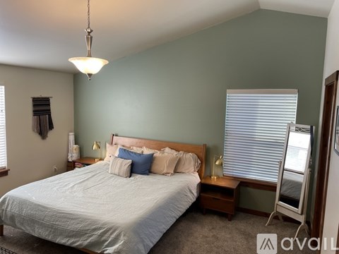A bedroom with a bed, nightstand, and window with blinds.