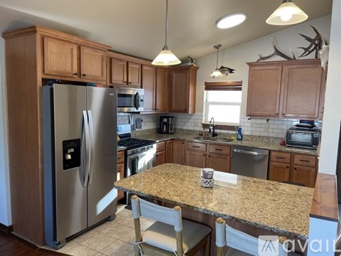 A kitchen with a granite counter top and a stainless steel refrigerator.