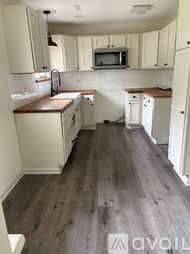A kitchen with white cabinets and a wooden floor.