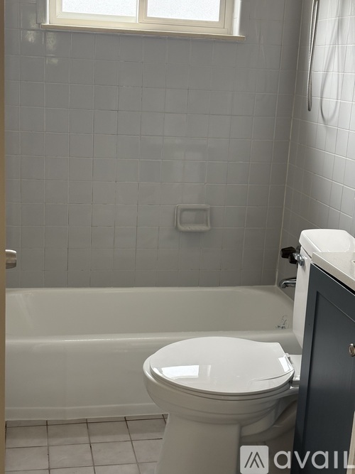 A white toilet in a bathroom with grey tiled walls.