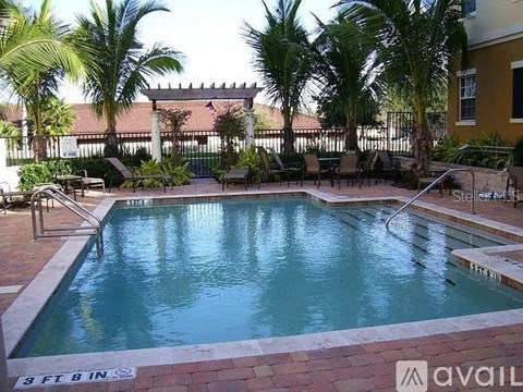 A pool surrounded by palm trees and a fence.