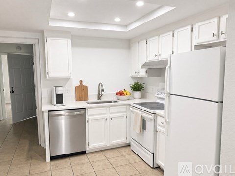 A white kitchen with a refrigerator, sink, and oven.