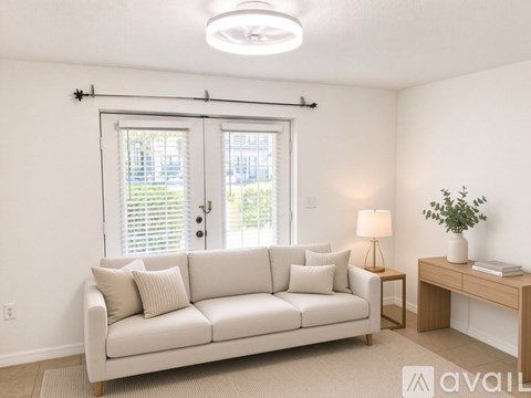 A living room with a white couch and a lamp on a side table.