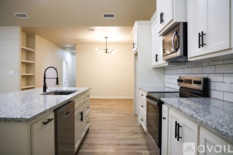 A kitchen with white cabinets and granite countertops is available for rent.