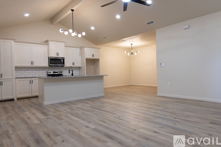 A kitchen with a white countertop and cabinets, a microwave, and a ceiling fan.