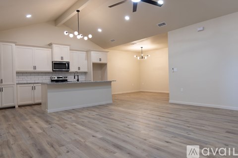 A kitchen with a white countertop and cabinets, a microwave, and a ceiling fan.