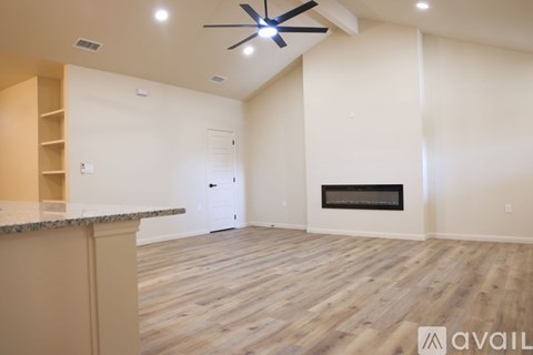 A spacious living room with a fireplace and a ceiling fan.