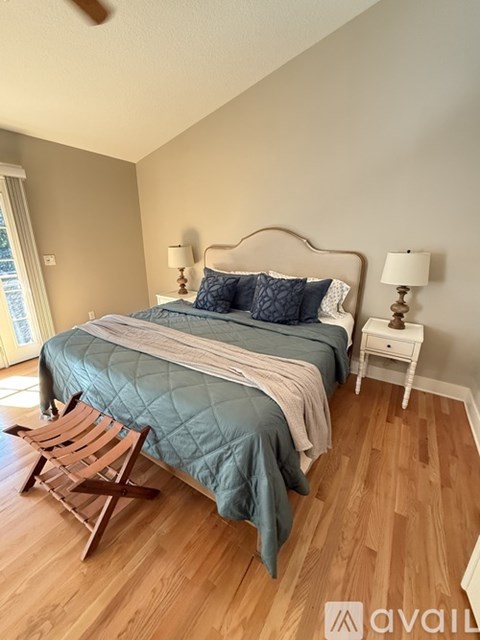 A bedroom with a bed, a chair, and two lamps.