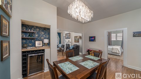 A dining room with a table set for six and a chandelier hanging from the ceiling.