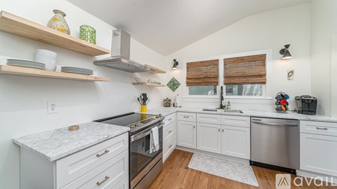 A kitchen with white cabinets and a black countertop.