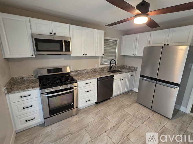 A kitchen with white cabinets and a stainless steel refrigerator.