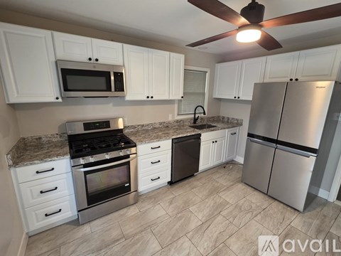 A kitchen with white cabinets and a stainless steel refrigerator.