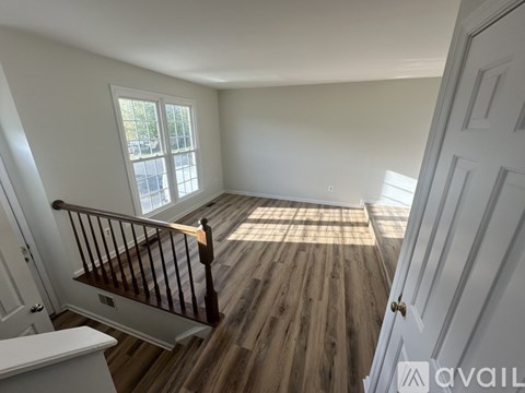 A room with wooden floors and a window with a view of a parking lot.
