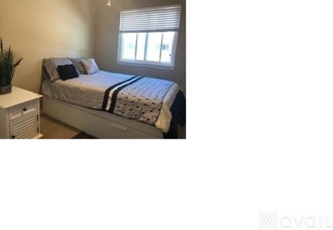 A bedroom with a bed, a nightstand, and a window.