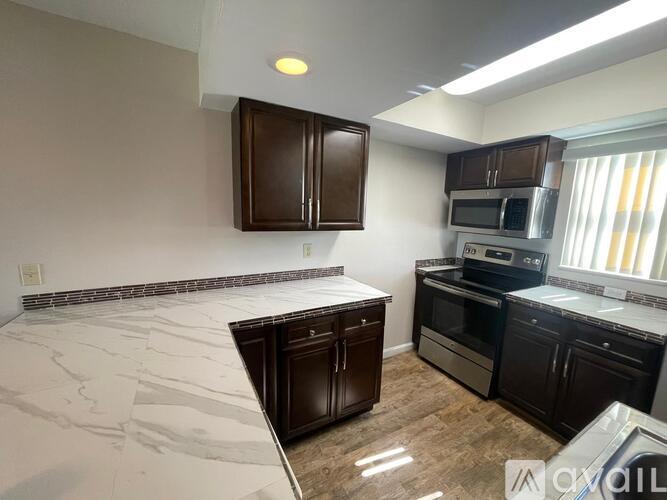 A kitchen with dark brown cabinets and a marble countertop.
