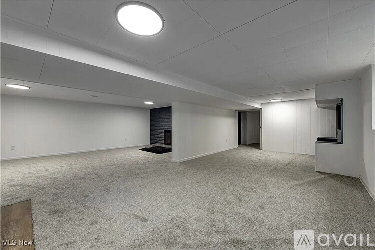 A spacious empty room with a carpeted floor and white walls.