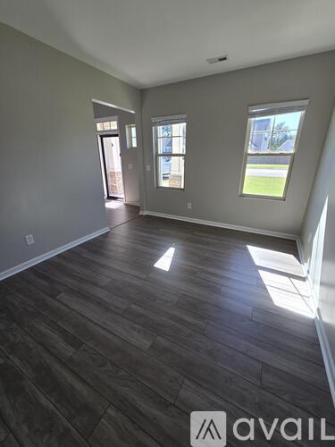 A spacious room with wooden flooring and large windows.