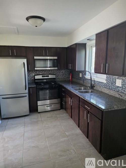 A kitchen with dark wood cabinets and a granite countertop.
