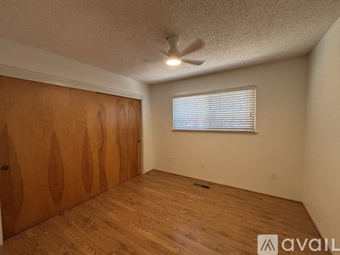 A room with wooden floors and a window with blinds.