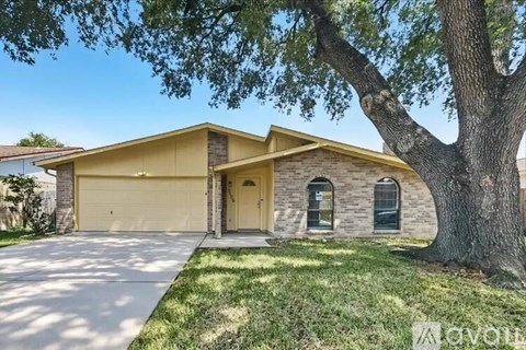 A house with a garage and a tree in front.